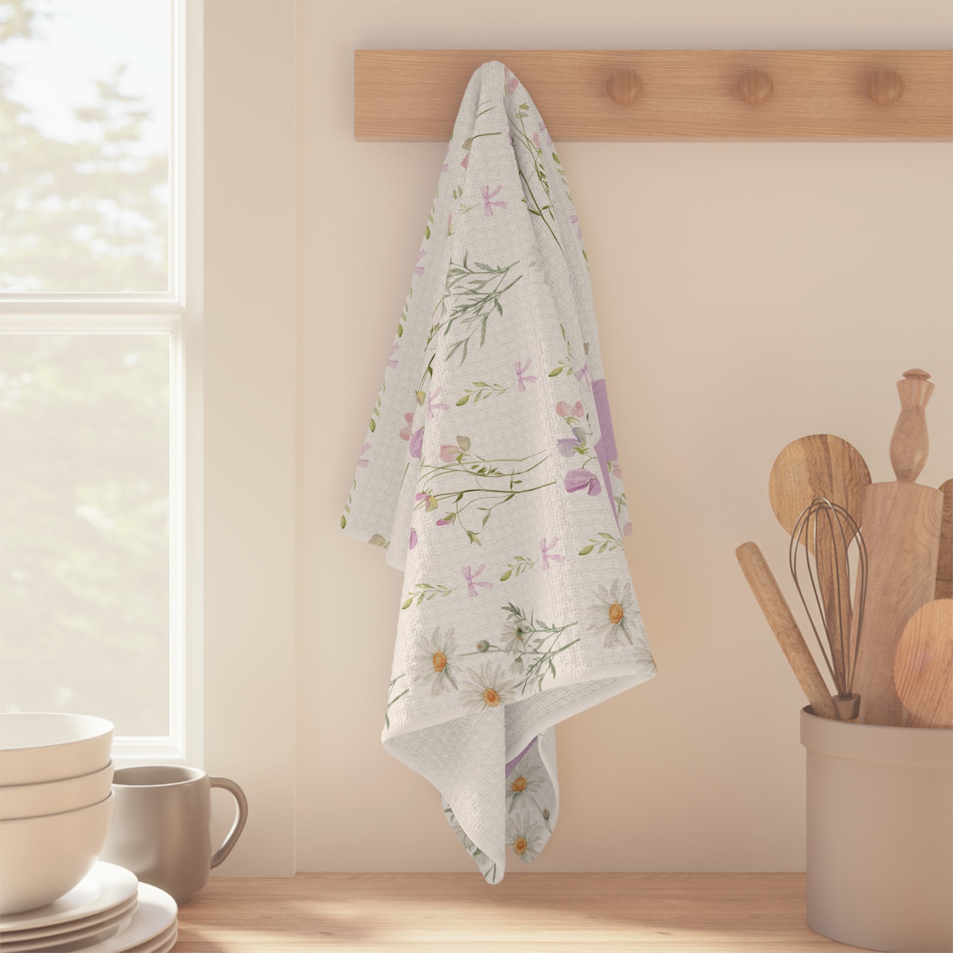 White microfiber tea towel with watercolor daisies and sweet pea blooms, hanging on a wooden peg.