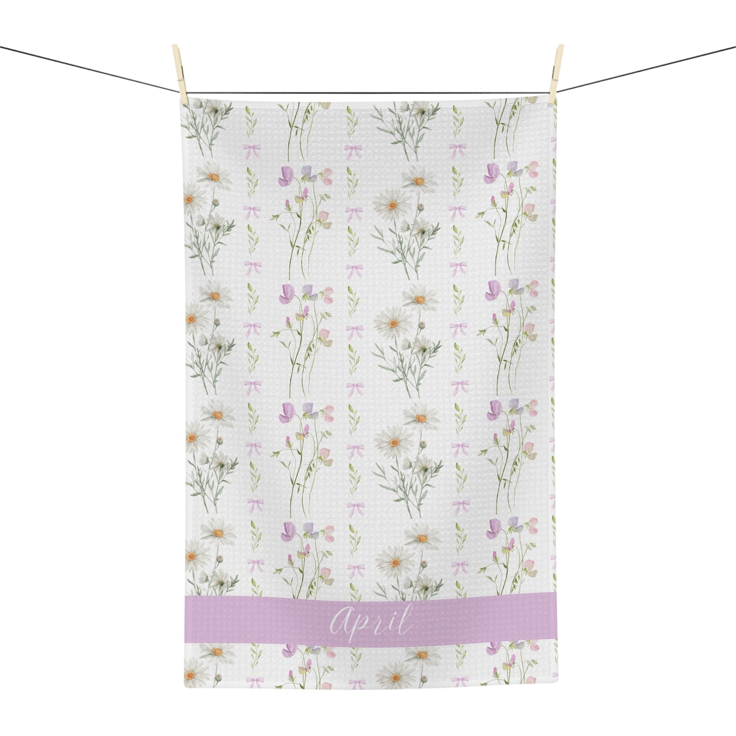 White microfiber tea towel with watercolor daisies, sweet peas, and "April" on a lavender band.