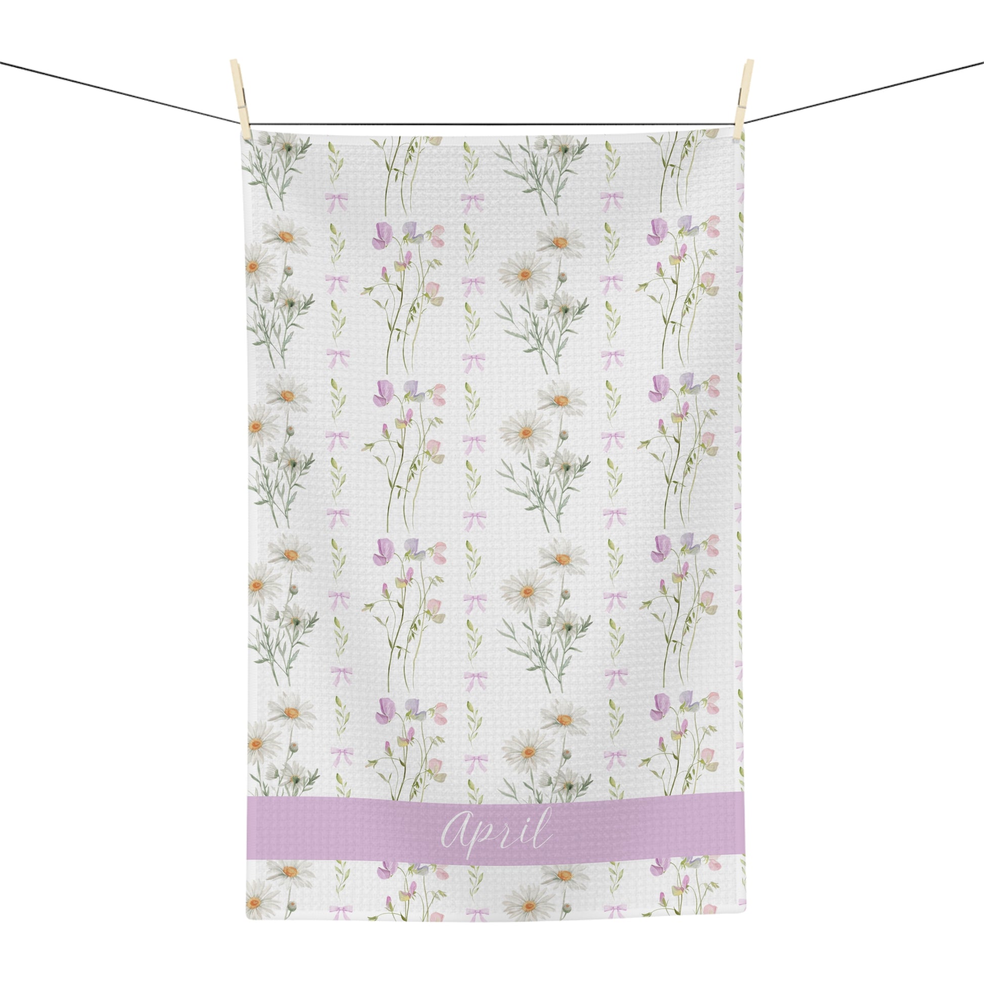 White microfiber tea towel with watercolor daisies, sweet peas, and "April" on a lavender band.