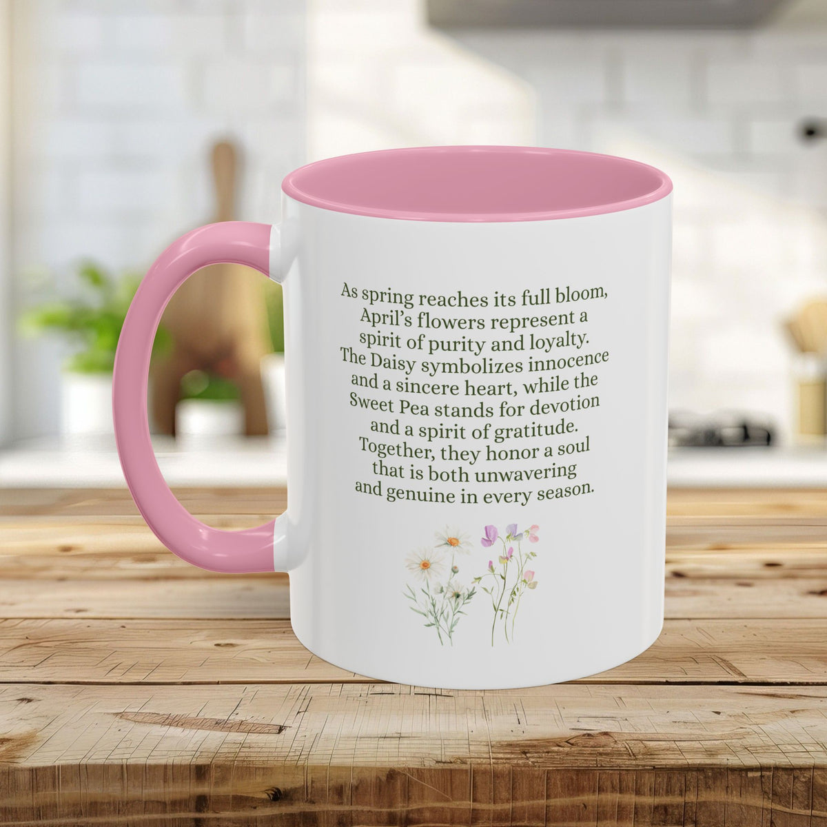 White ceramic mug with pink handle and interior, featuring April birth flower text and daisy/sweet pea illustration.