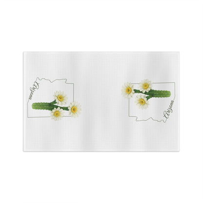 White microfiber tea towel with two Arizona state outlines, each featuring a saguaro cactus bloom and "Arizona" in cursive.