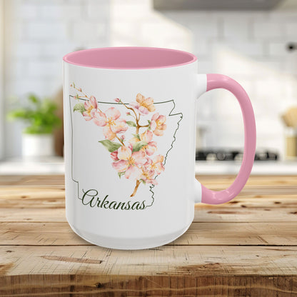 15oz glossy ceramic mug with pink interior/handle, featuring watercolor apple blossoms over an Arkansas outline.