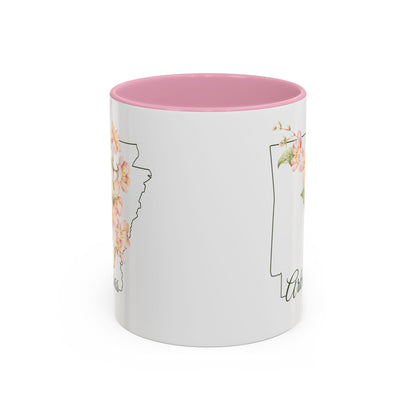 White ceramic mug with pink interior, featuring a watercolor apple blossom design over an outline of Arkansas.