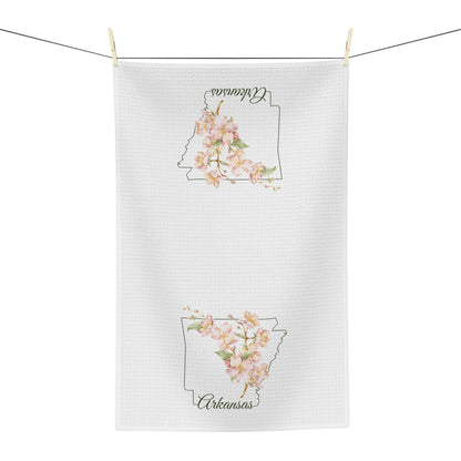 White microfiber tea towel with a watercolor Arkansas silhouette and pink apple blossoms, hanging on a line.