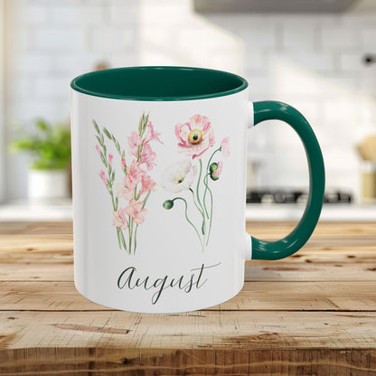 White 11oz ceramic mug with green handle and interior, featuring watercolor gladiolus and poppy blooms, and "August" script.