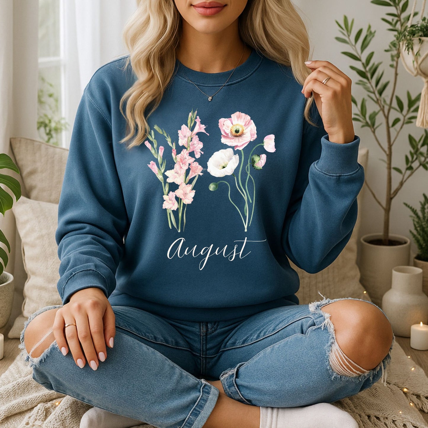 Woman wearing a blue August birth month flower sweatshirt with watercolor gladiolus and poppy blooms.