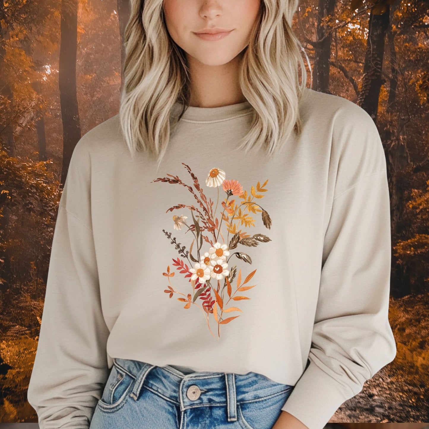 Woman in a beige long sleeve tee with a watercolor autumn wildflower and botanical design.