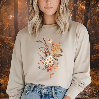 Woman in a beige long sleeve tee with a watercolor autumn wildflower and botanical design.