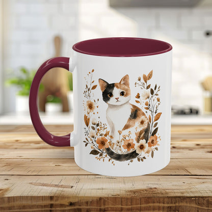 White ceramic mug with a watercolor calico cat and autumnal florals, featuring a black interior and handle.