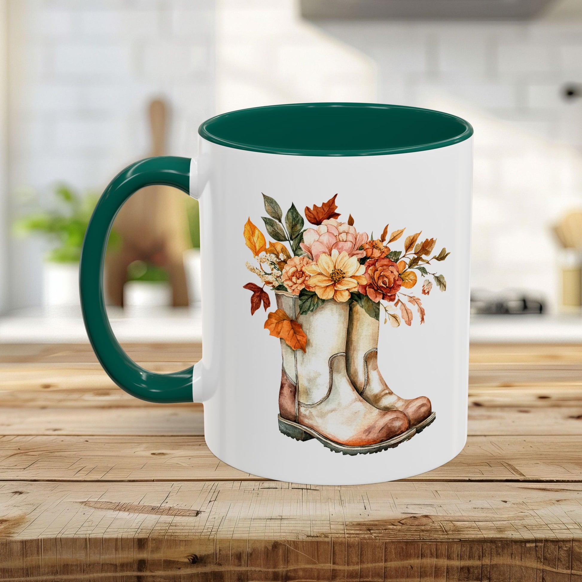White ceramic mug with a dark green handle and interior, featuring a watercolor design of worn boots overflowing with autumn flowers.