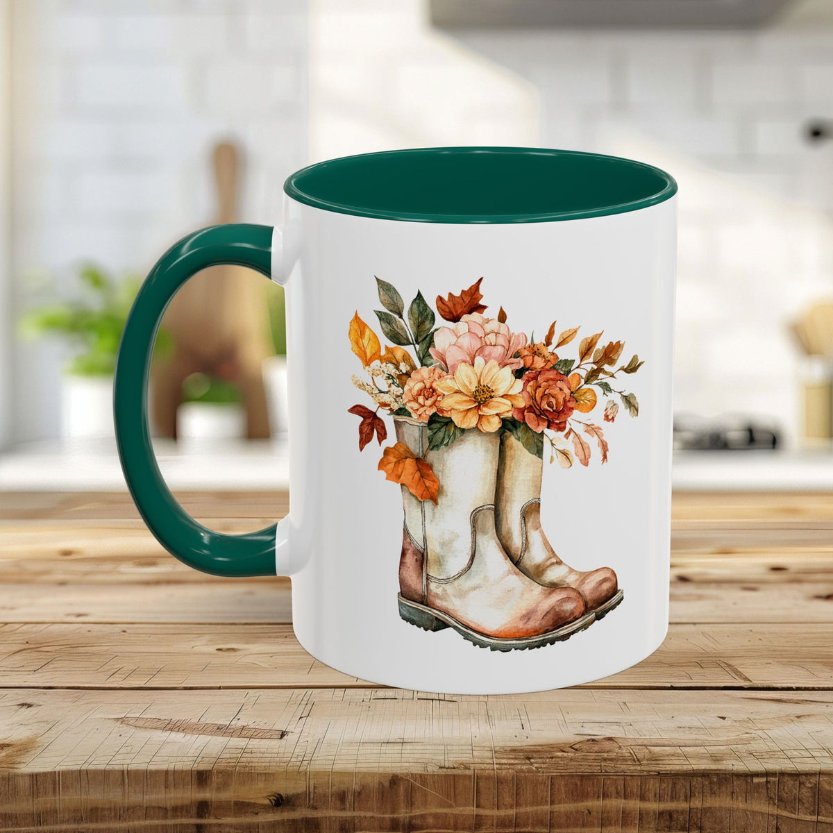 White ceramic mug with a dark green handle and interior, featuring a watercolor design of worn boots overflowing with autumn flowers.