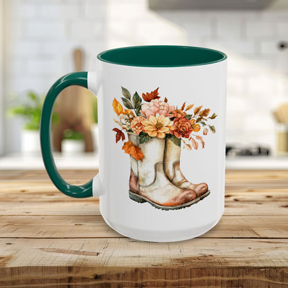 White ceramic mug with a green handle and interior, featuring watercolor cowboy boots overflowing with autumn flowers.