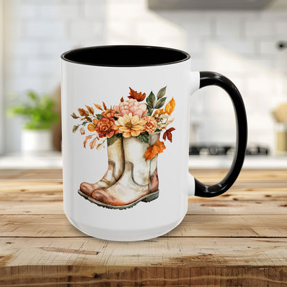 15oz white ceramic mug with black handle and interior, featuring watercolor cowboy boots overflowing with autumn flowers.