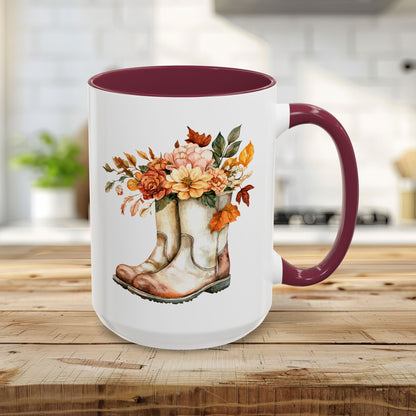 15oz ceramic mug with maroon handle and interior, featuring watercolor cowboy boots overflowing with autumn flowers.