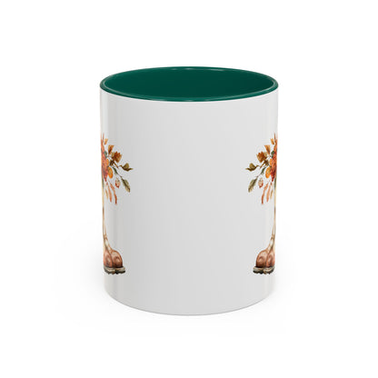White ceramic mug with green interior and handle, featuring a watercolor design of cowboy boots overflowing with autumn flowers.