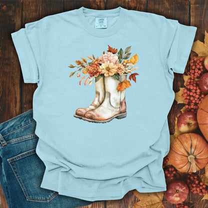 Light blue relaxed-fit tee with watercolor cowboy boots and autumn flowers, beside jeans and fall decor.
