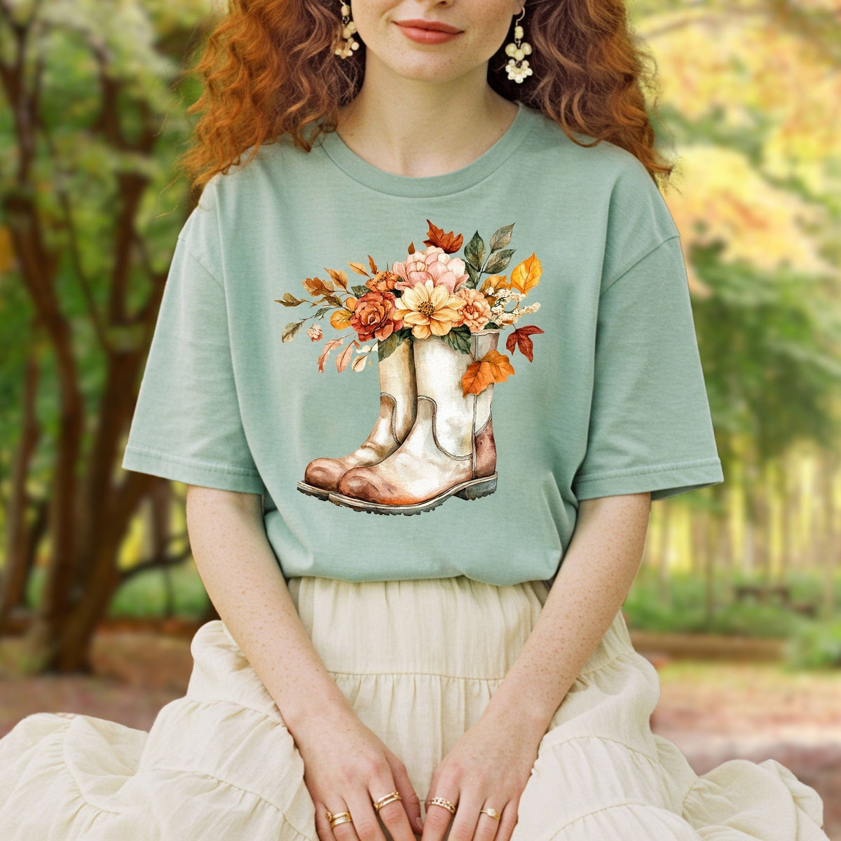 Relaxed-fit, garment-dyed sage green cotton t-shirt with watercolor cowboy boots and autumn flowers.