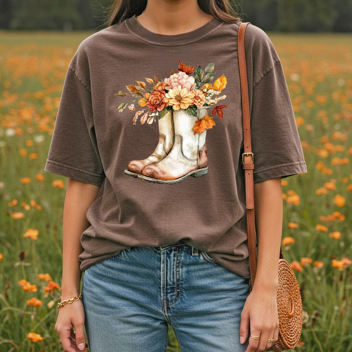 Relaxed-fit, garment-dyed brown t-shirt with a watercolor illustration of white cowboy boots filled with autumn flowers.