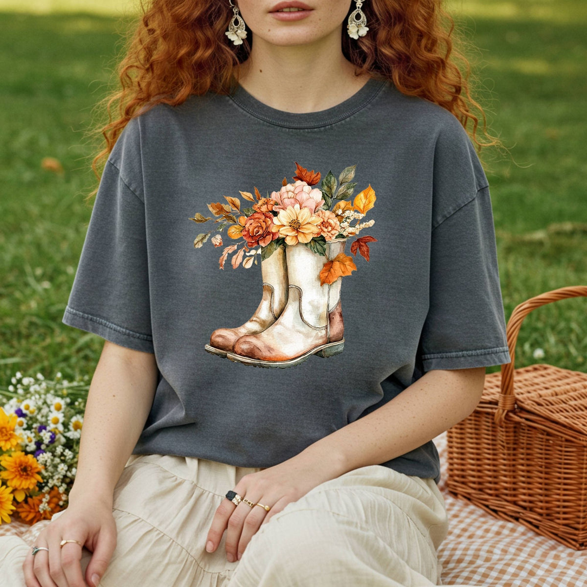 Charcoal garment-dyed tee with watercolor cowboy boots brimming with autumn flowers, worn by a person on a picnic blanket.