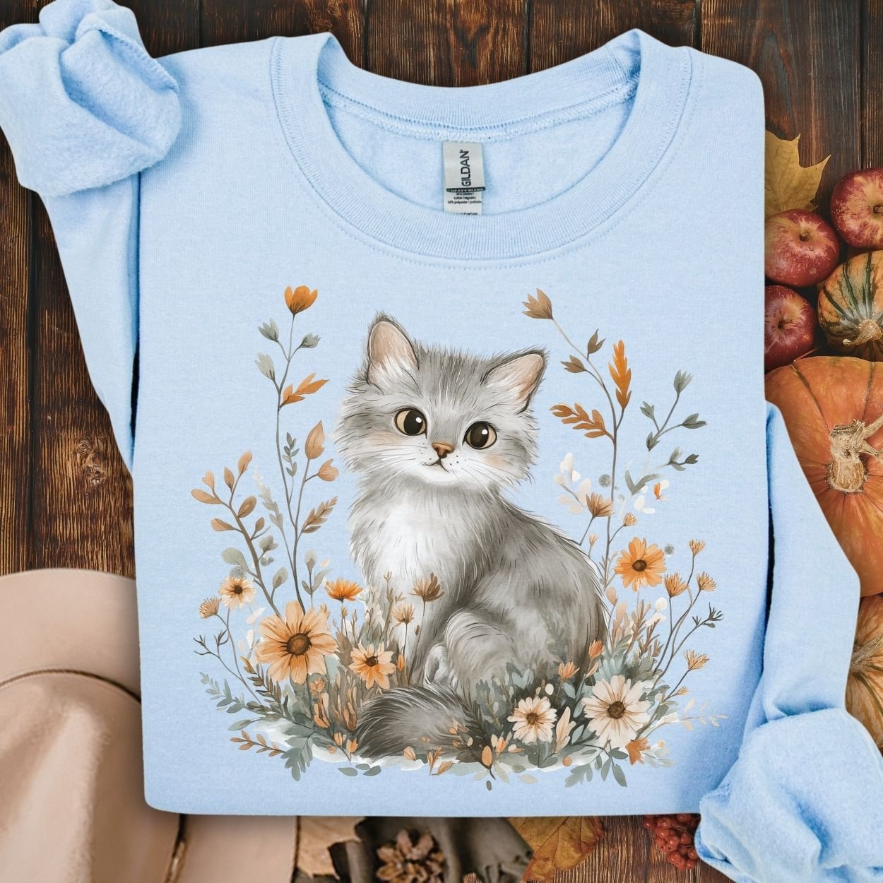 Light blue crewneck sweatshirt with a grey kitten among autumn wildflowers.