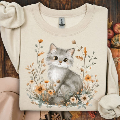 Sand crewneck sweatshirt with a grey kitten among autumn wildflowers.
