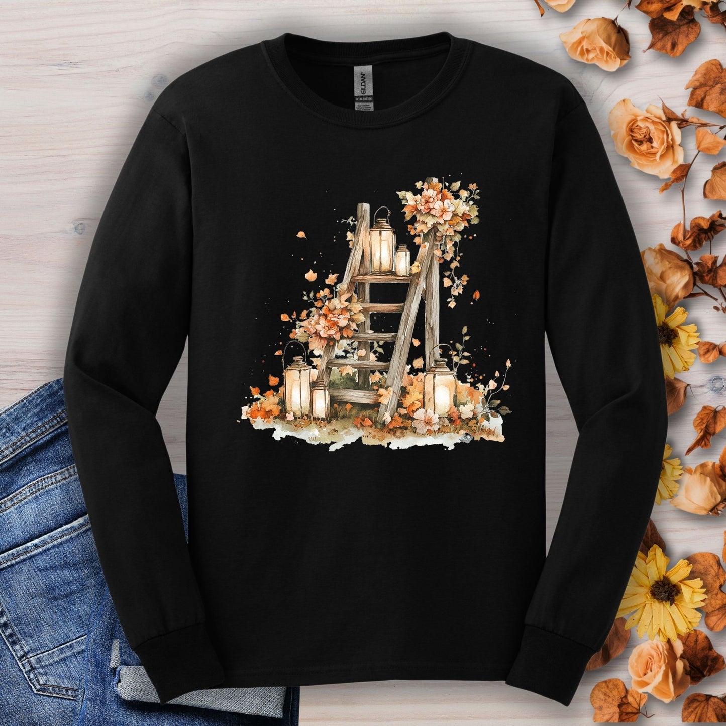 Black long sleeve tee with watercolor autumn lanterns, flowers, and leaves on a rustic ladder.