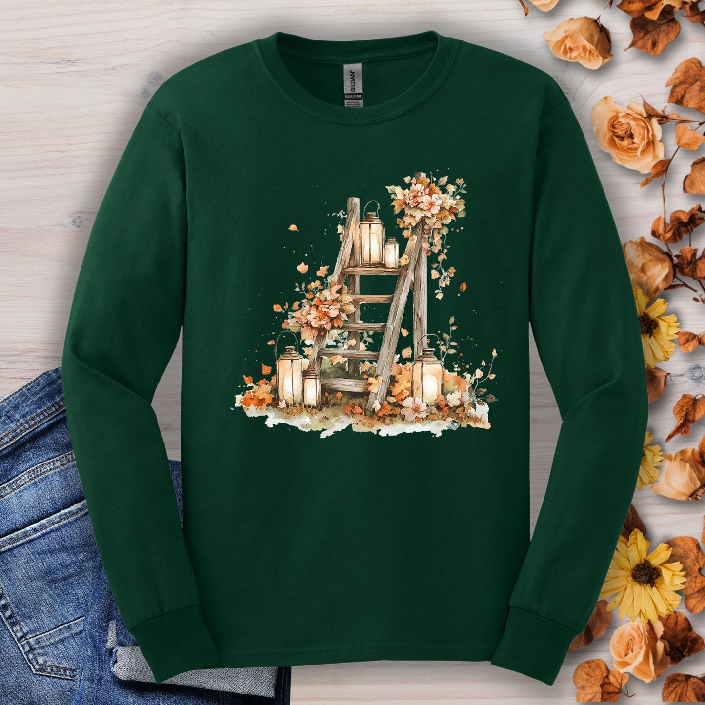 Forest Green long sleeve tee with watercolor autumn lanterns, flowers, and leaves on a rustic ladder.