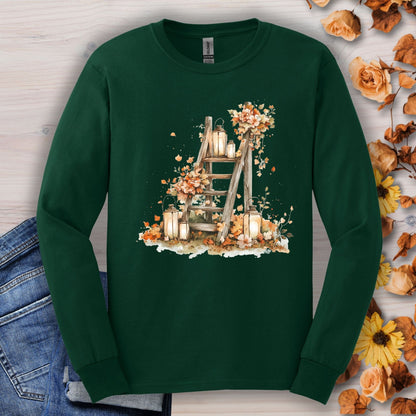 Forest Green long sleeve tee with watercolor autumn lanterns, flowers, and leaves on a rustic ladder.