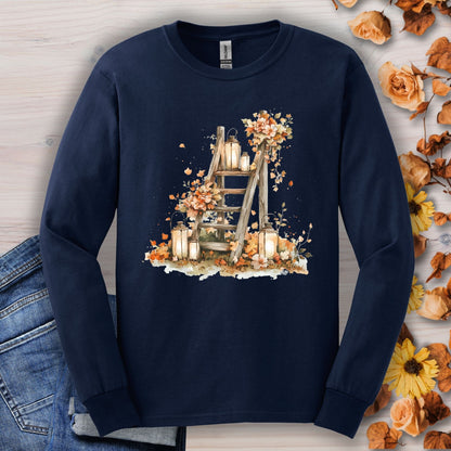 Navy long sleeve tee with watercolor autumn lanterns, flowers, and leaves on a rustic ladder.