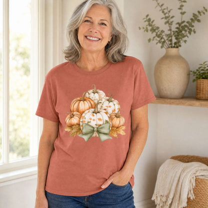 Woman in a rust-colored Comfort Colors tee with watercolor pumpkins, autumn leaves, and a sage green bow.