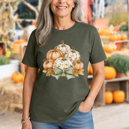 Woman in a relaxed-fit, garment-dyed olive green t-shirt with watercolor pumpkins, fall leaves, and a sage green bow.