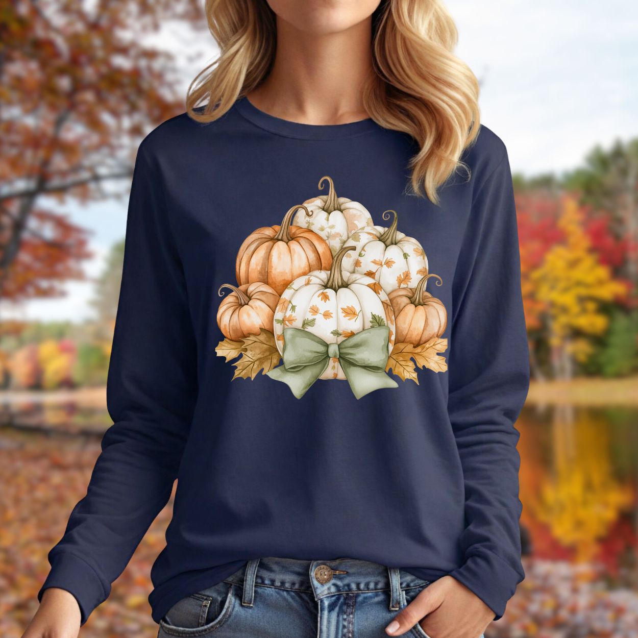 Navy long sleeve tee with a watercolor pumpkin and sage bow design, worn by a woman outdoors in autumn.