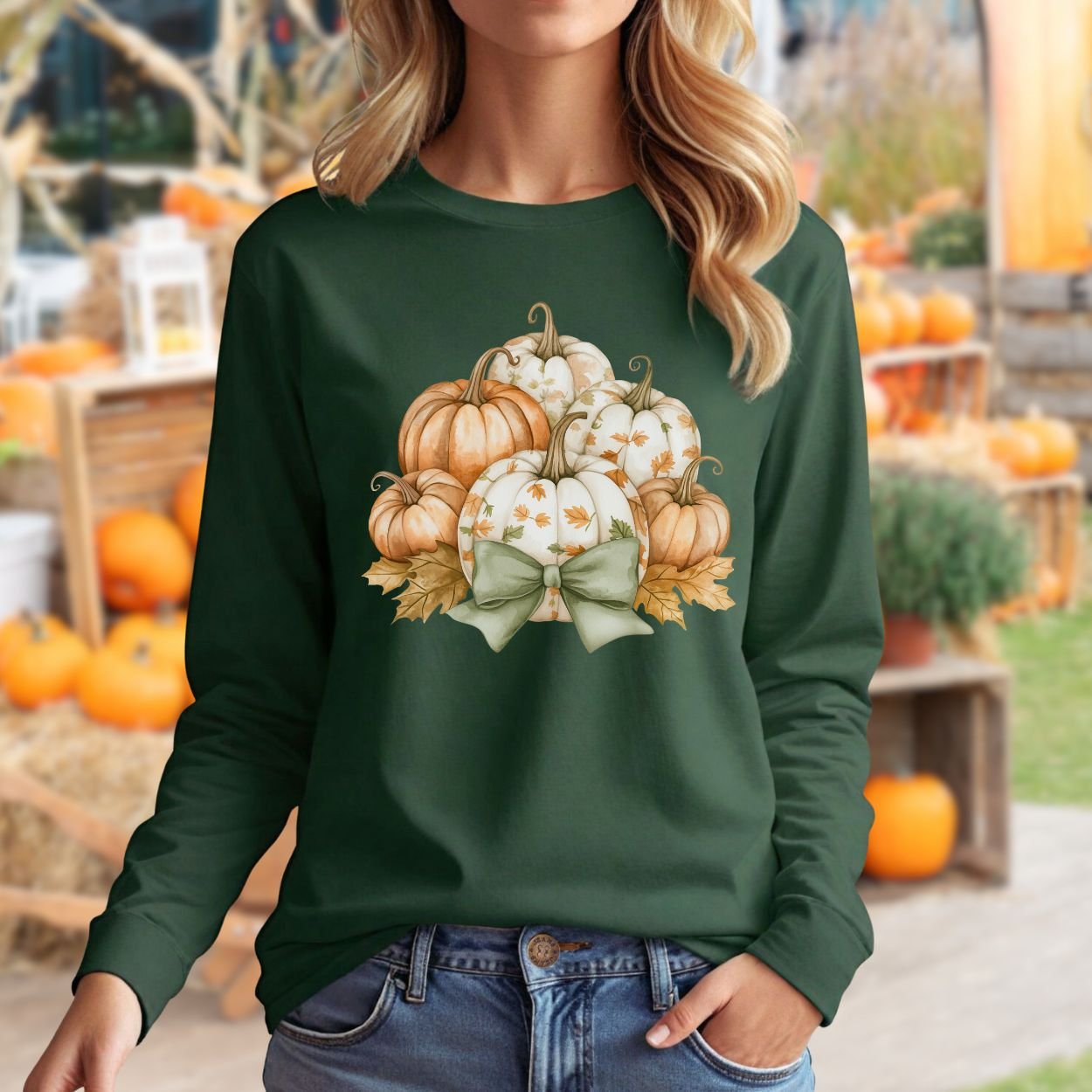 Dark green long-sleeve tee with a watercolor pumpkin and sage bow design, worn by a woman in a fall setting.