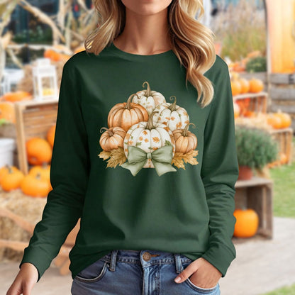 Dark green long-sleeve tee with a watercolor pumpkin and sage bow design, worn by a woman in a fall setting.