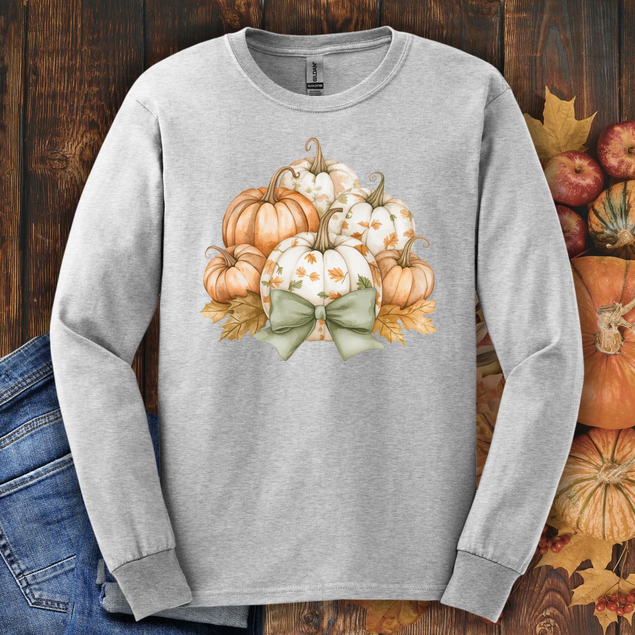 Ash long sleeve tee with watercolor terracotta and cream pumpkins, sage bow, and autumn leaves.