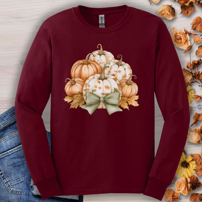 Maroon long-sleeve tee with a watercolor pumpkin and sage bow design, surrounded by autumn leaves.