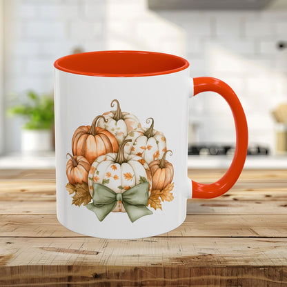 White 11oz ceramic mug with orange interior/handle, featuring a watercolor pumpkin bouquet and green bow.