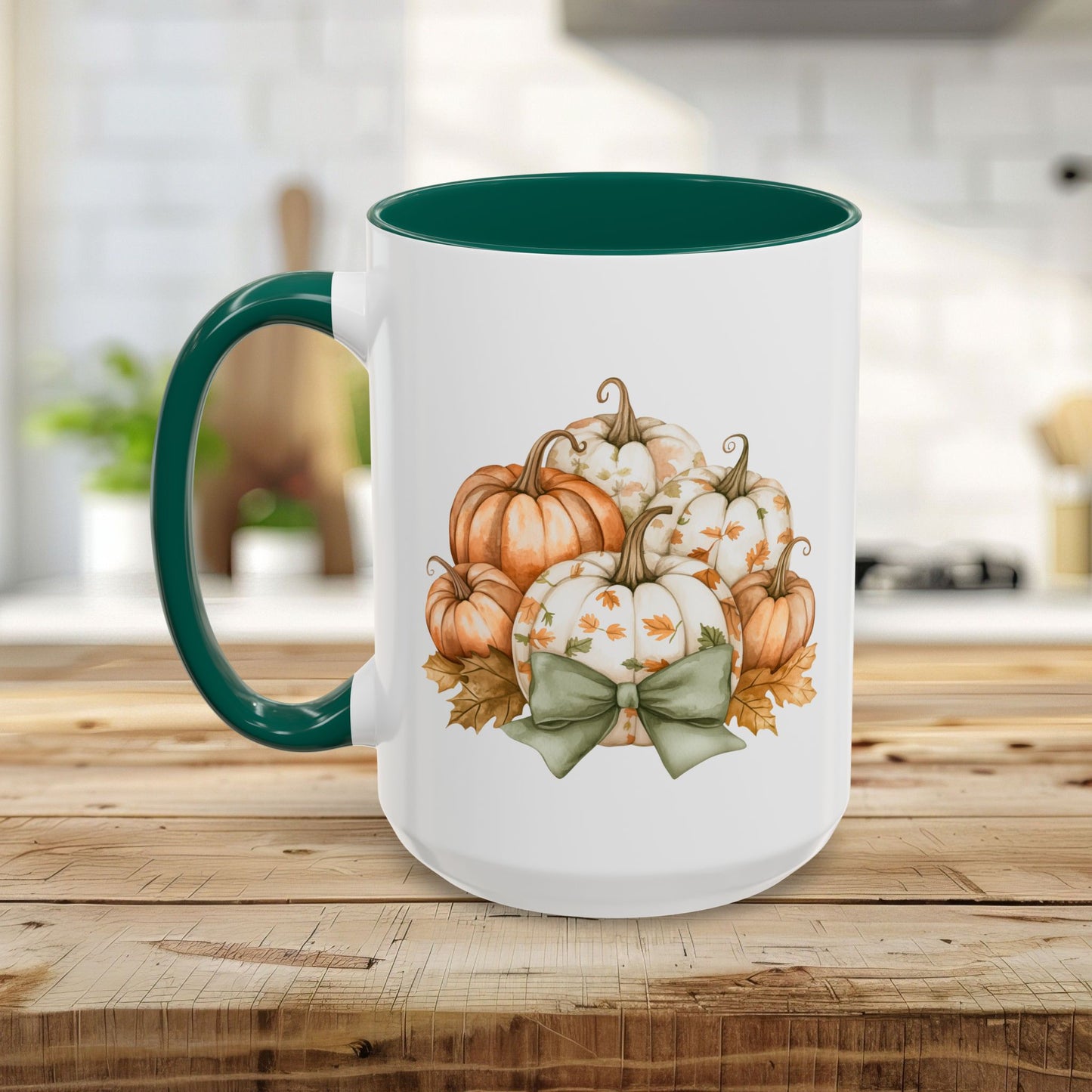 White ceramic mug with green handle and interior, featuring a watercolor print of autumn pumpkins and a sage green bow.