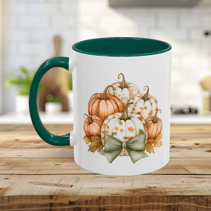White ceramic mug with green interior and handle, featuring a watercolor print of autumn pumpkins and a sage bow.