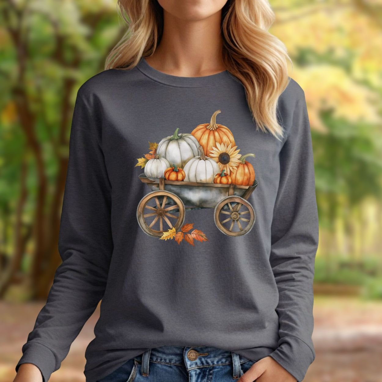 Woman wearing a charcoal long-sleeve tee with a watercolor wagon full of white and orange pumpkins.