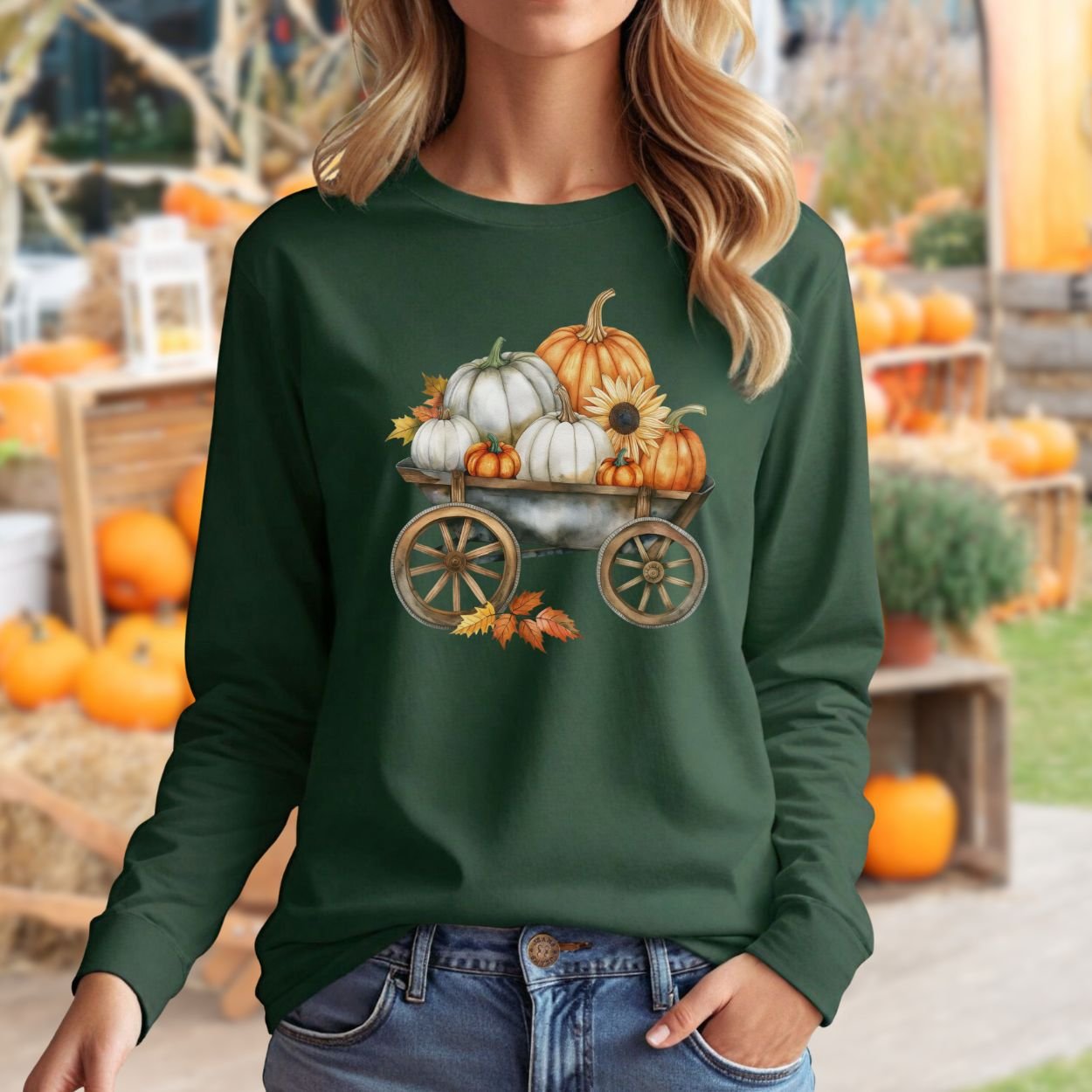 Woman in a dark green long sleeve tee with a watercolor wagon of white and orange pumpkins.