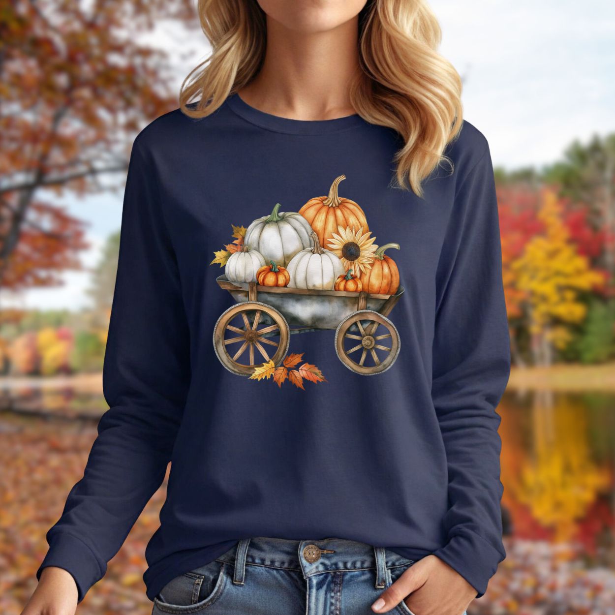 Navy long sleeve tee with a watercolor wagon full of white and orange pumpkins and fall leaves.