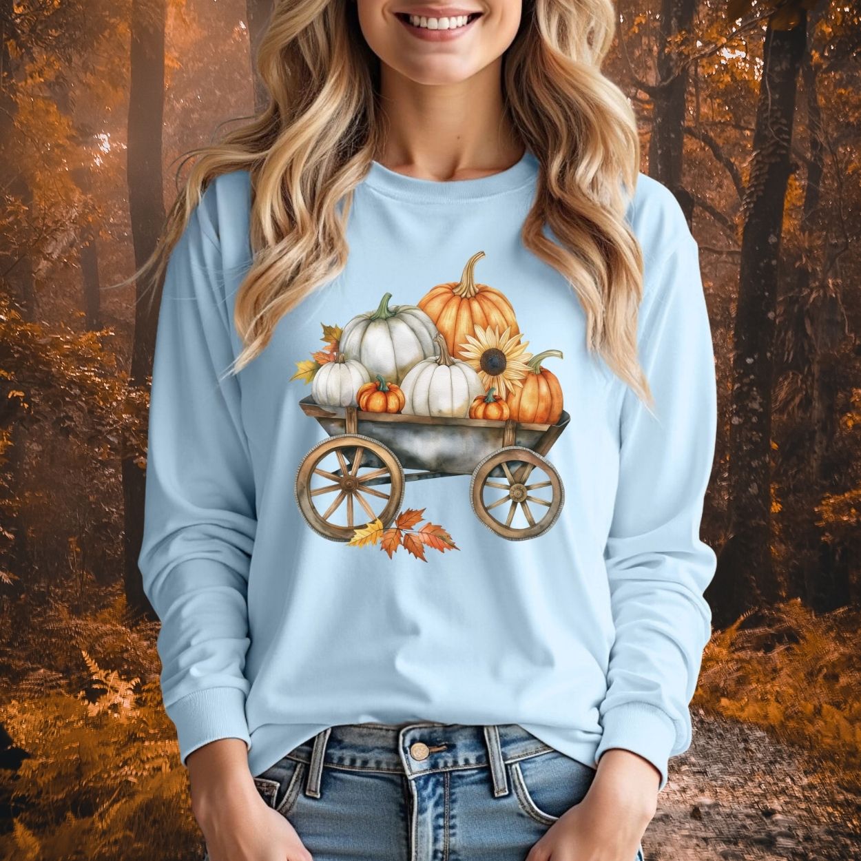 Light blue long sleeve tee with a watercolor wagon full of white and orange pumpkins, sunflower, and fall leaves.