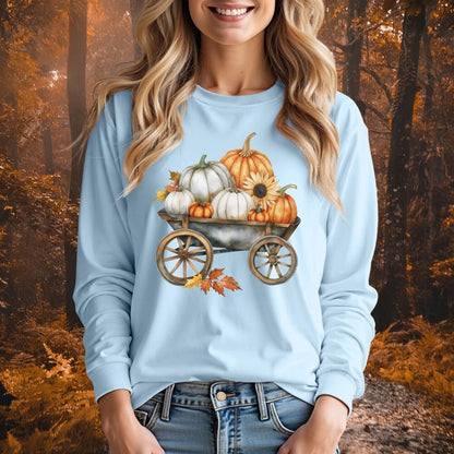 Light blue long sleeve tee with a watercolor wagon full of white and orange pumpkins, sunflower, and fall leaves.