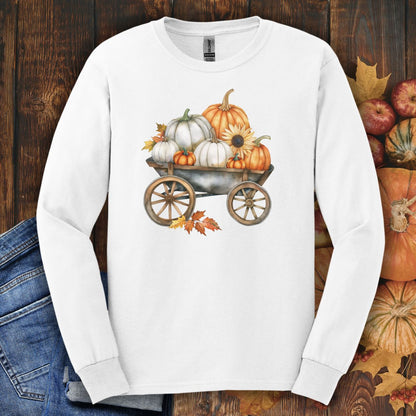 White long-sleeve tee with a watercolor wagon full of white and orange pumpkins and fall leaves.