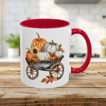 White ceramic mug with red rim and handle, featuring a watercolor autumn pumpkin harvest wagon design.