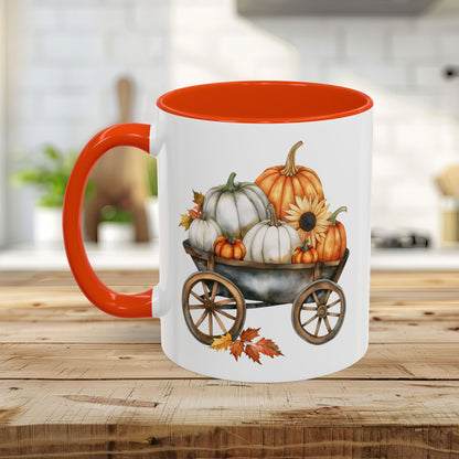 White ceramic mug with an orange interior and handle, featuring a watercolor print of pumpkins in a rustic wagon.