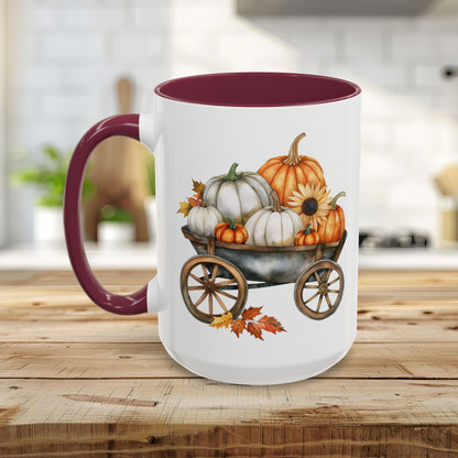 White ceramic mug with a burgundy rim and handle, featuring a watercolor-style autumn wagon filled with pumpkins and a sunflower.