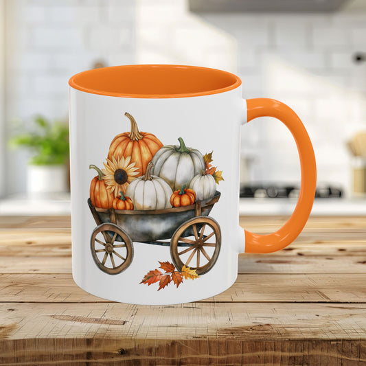 White ceramic mug with an orange rim and handle, featuring a watercolor-style autumn pumpkin harvest wagon design.
