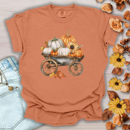 Yam-colored, relaxed-fit cotton t-shirt with a watercolor rustic wagon piled with white and orange pumpkins and sunflowers.